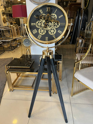 Tripodklocka med guldfärgat metallhjul – svarta träben (150 × 45 cm)