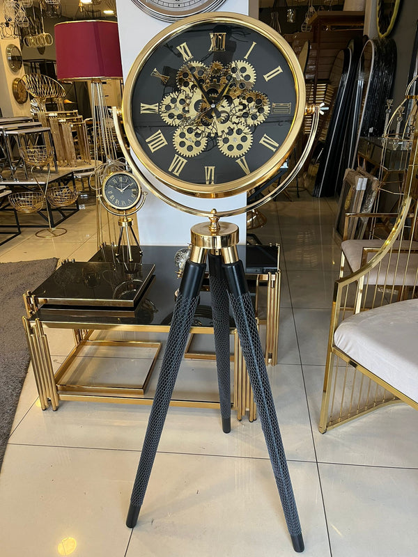 Tripodklocka med guldfärgat metallhjul – svarta träben (150 × 45 cm)